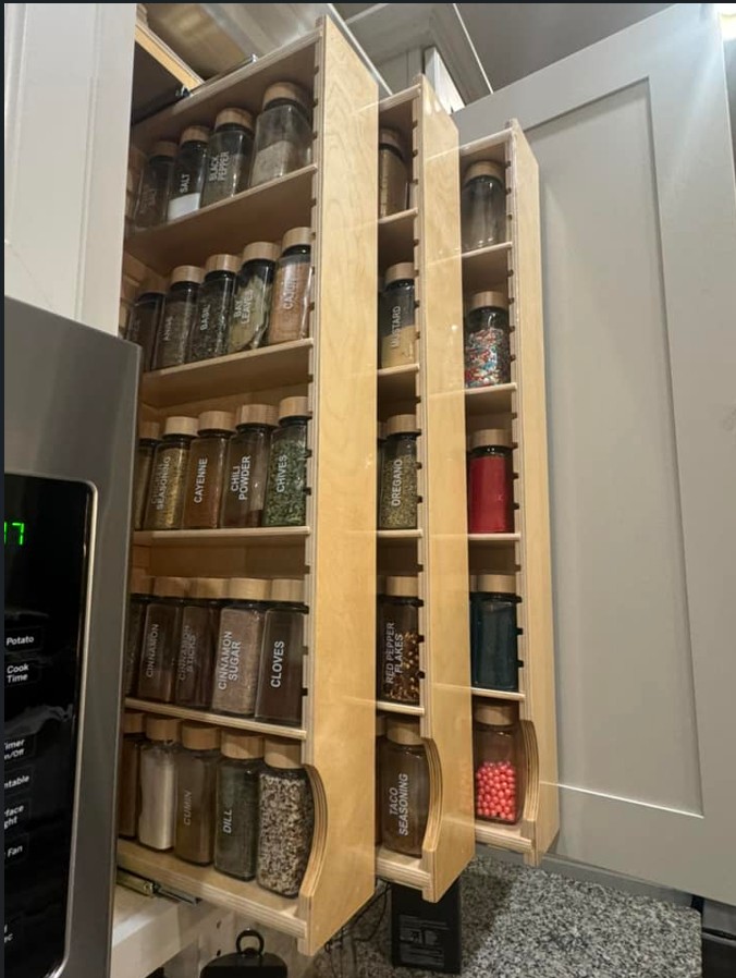 Three pull out shelves containing spices in upper cabinet