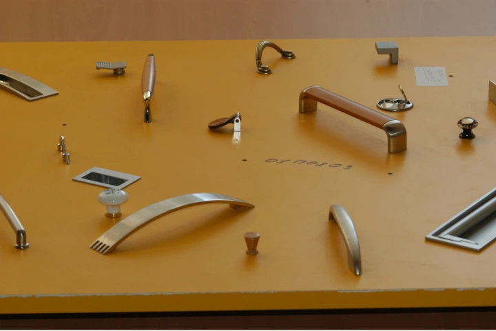 Selection of stylized cabinet pull and knobs on yellow background to replace kitchen drawers.